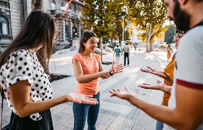 Gruppe junger Menschen unterhält sich mit Gebärdensprache im Freien.